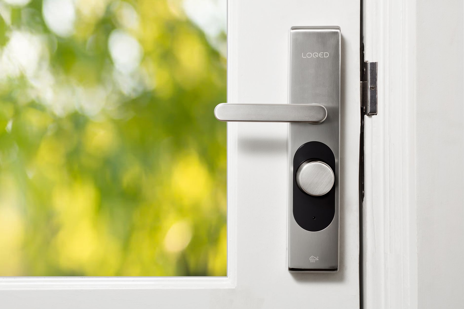 A hand entering a code on a keypad smart lock mounted on a front door