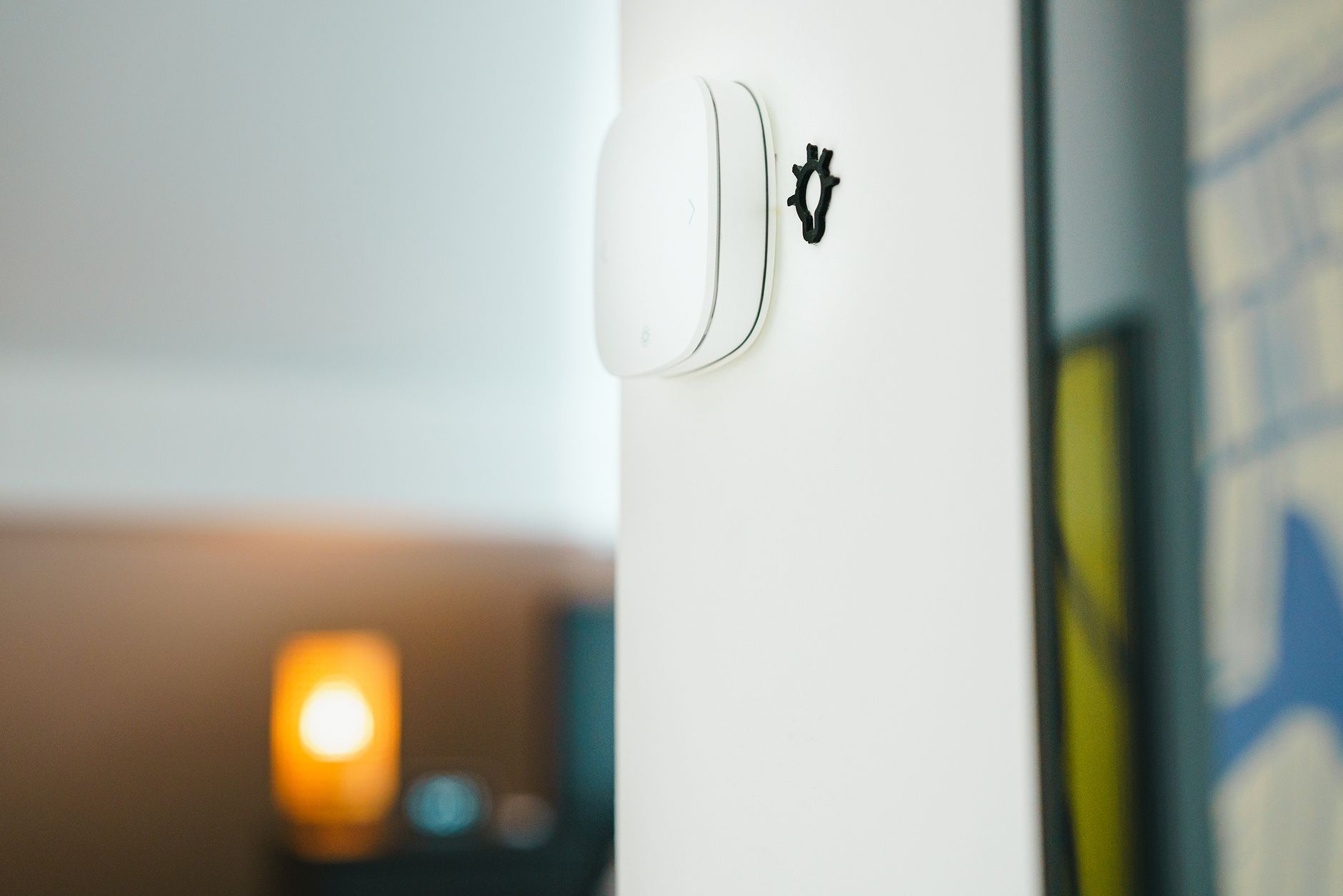 Smart light bulbs and a hub sitting on a wooden shelf beside a smartphone displaying a smart home app interface